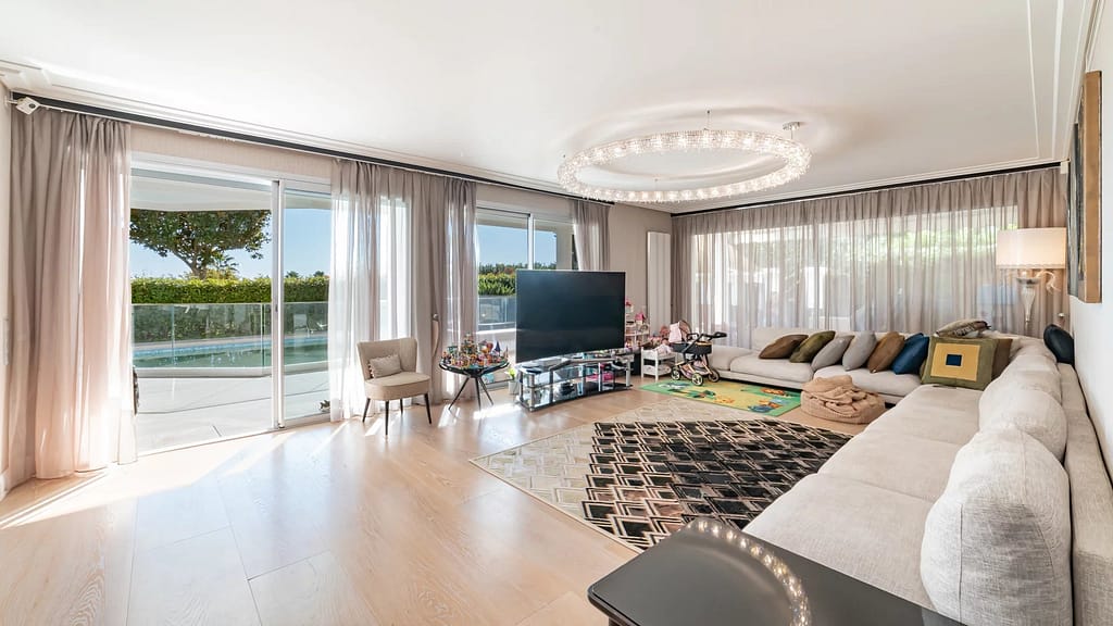 Image of a bright Croisette apartment living room with modern seating, large windows, and stunning sea views beyond.