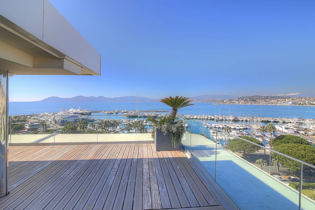 Image of a spacious terrace of a Luxury Cannes Apartments For Sale with outdoor seating and a stunning panoramic view of the sea.