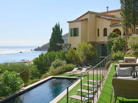 Image of a modern luxury villa with expansive glass walls, surrounded by greenery, illustrating the concept of how to find off-market luxury villas.