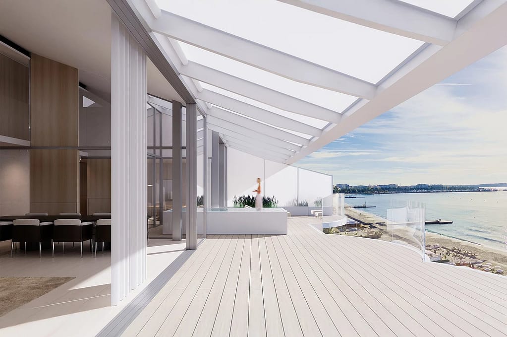 Image of a bright modern living room with large windows, neutral furnishings, and an open view of the sea outside.