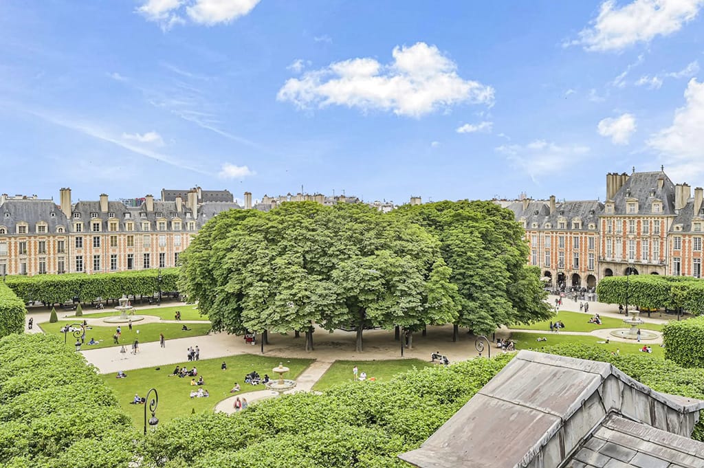Best (and Most Expensive) Neighborhoods to Buy Luxury Property in Paris 7 Photo of a central square in the 4th arrondissement of paris, france, with trees in the middle and surrounded by luxury apartment buildings.